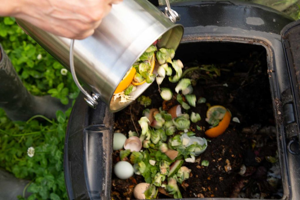 a person putting household waste into a compost bin